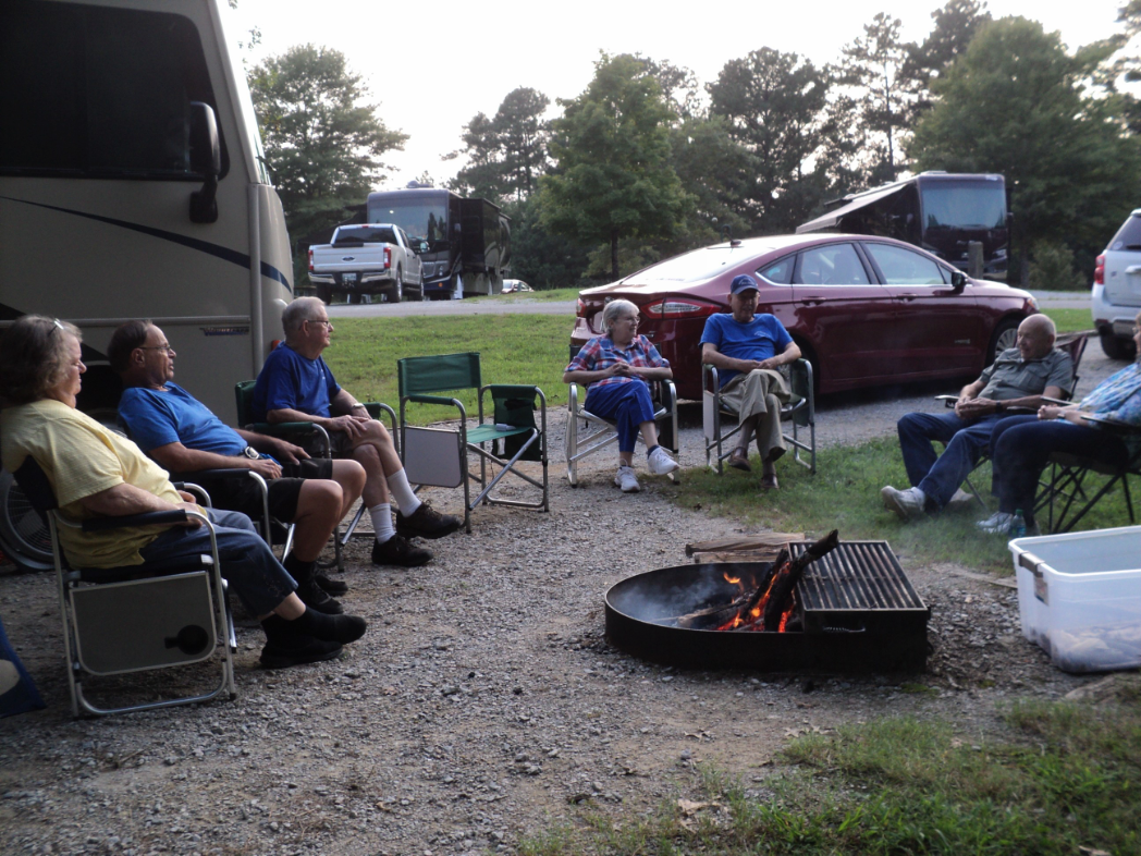 People sitting around a campfire at a campsite.